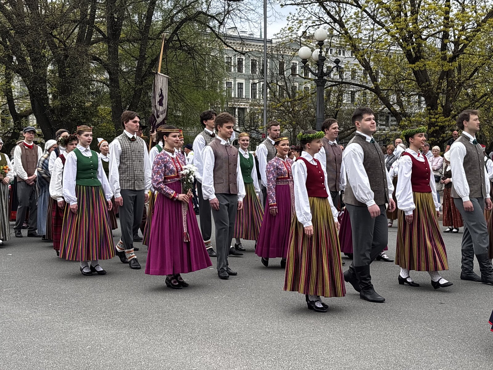 A folk-costume procession passes the Freedom Monument with the Latvian flag held high, Riga, 4 May