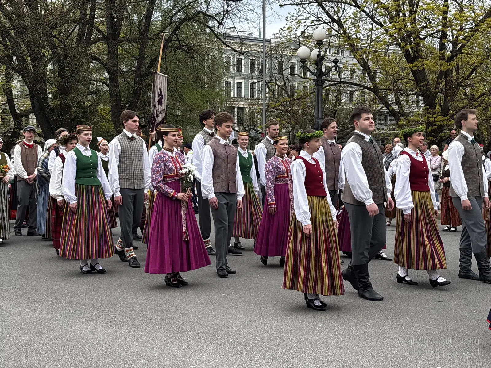 A folk-costume procession passes the Freedom Monument with the Latvian flag held high, Riga, 4 May