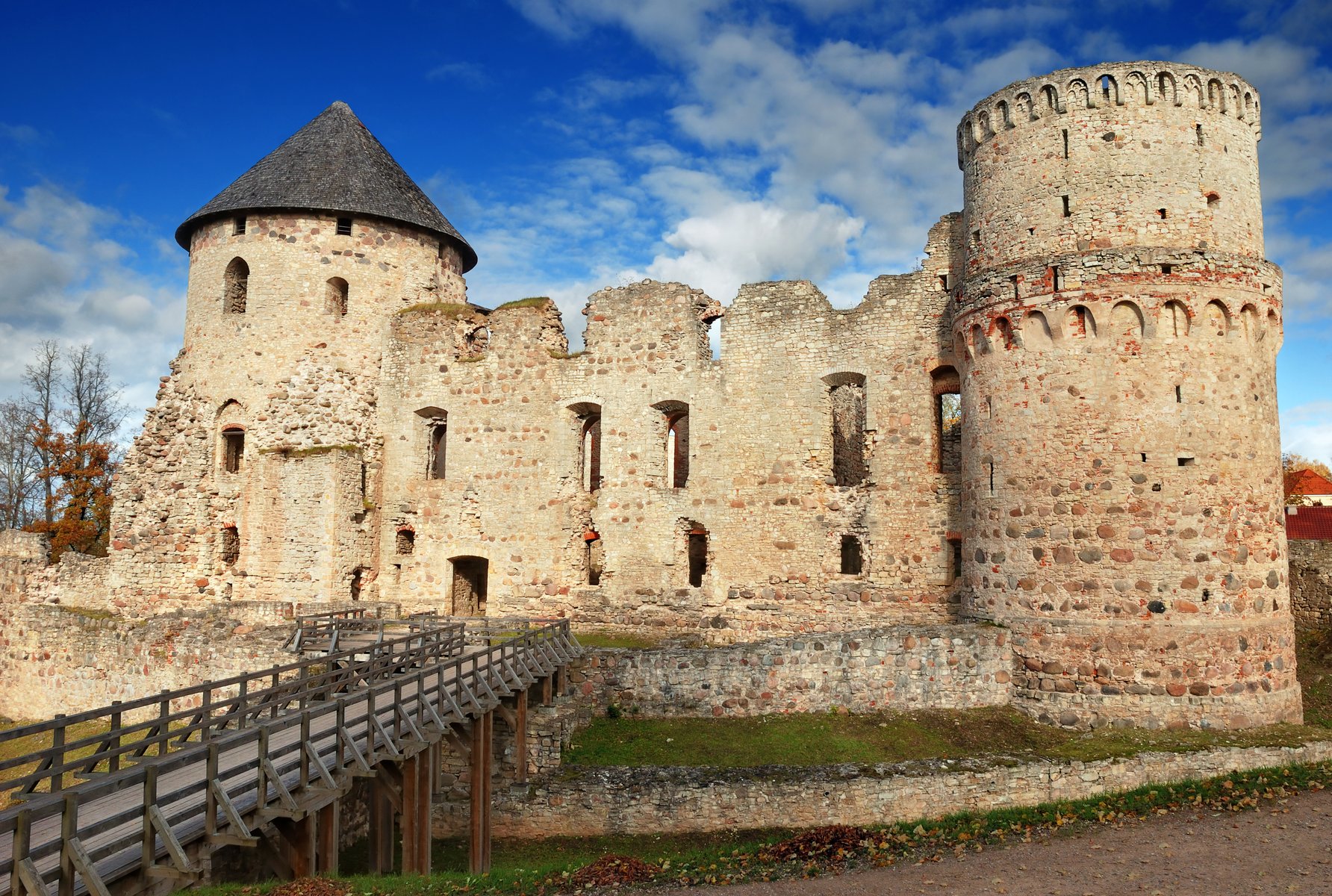 The red-walled towers of Cēsis Castle under a blue sky