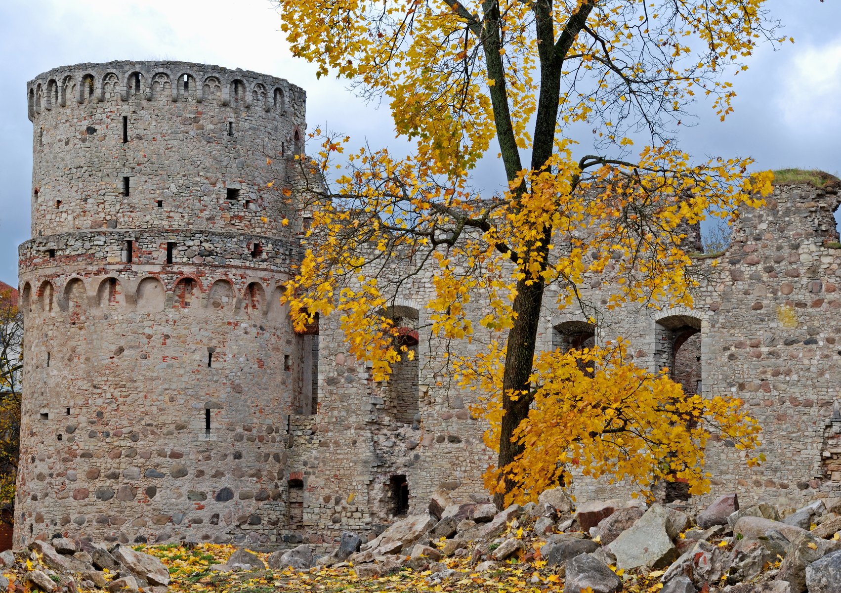 Cēsis Castle stone walls framed by golden autumn leaves