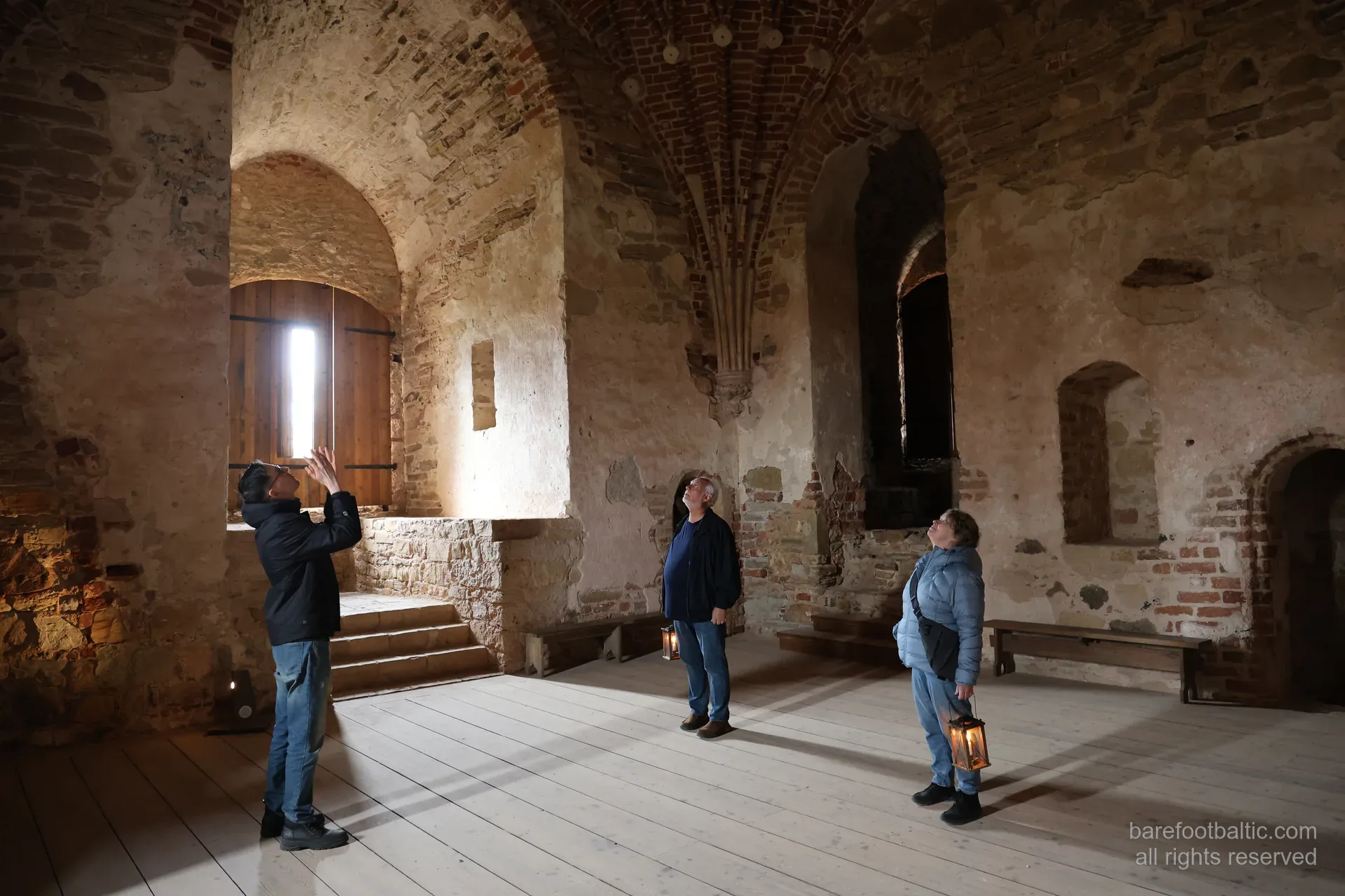 Guests with candle lanterns inside Cēsis Medieval Castle