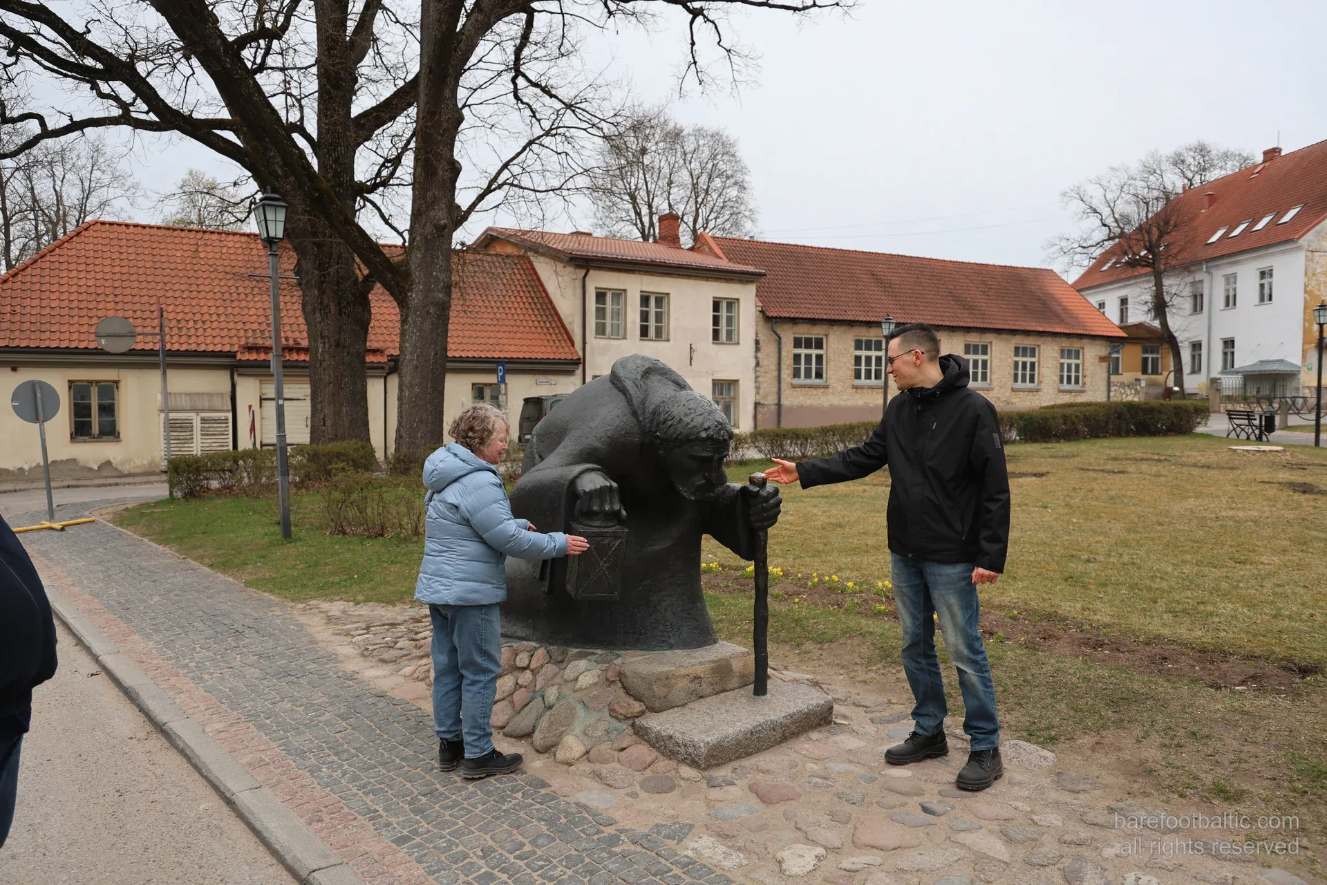 Tour group at the bronze pilgrim sculpture in Cēsis old town park