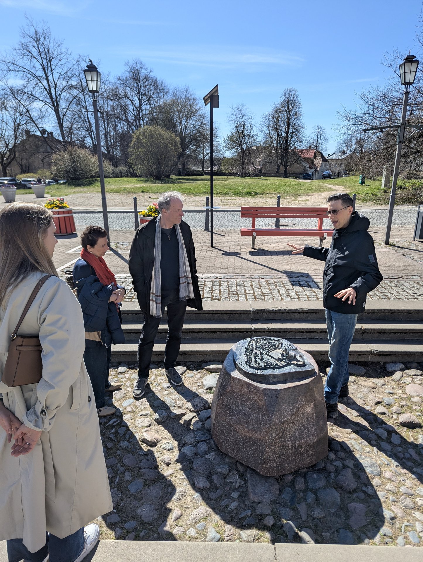 Guide explaining a historical marker stone in Cēsis old town