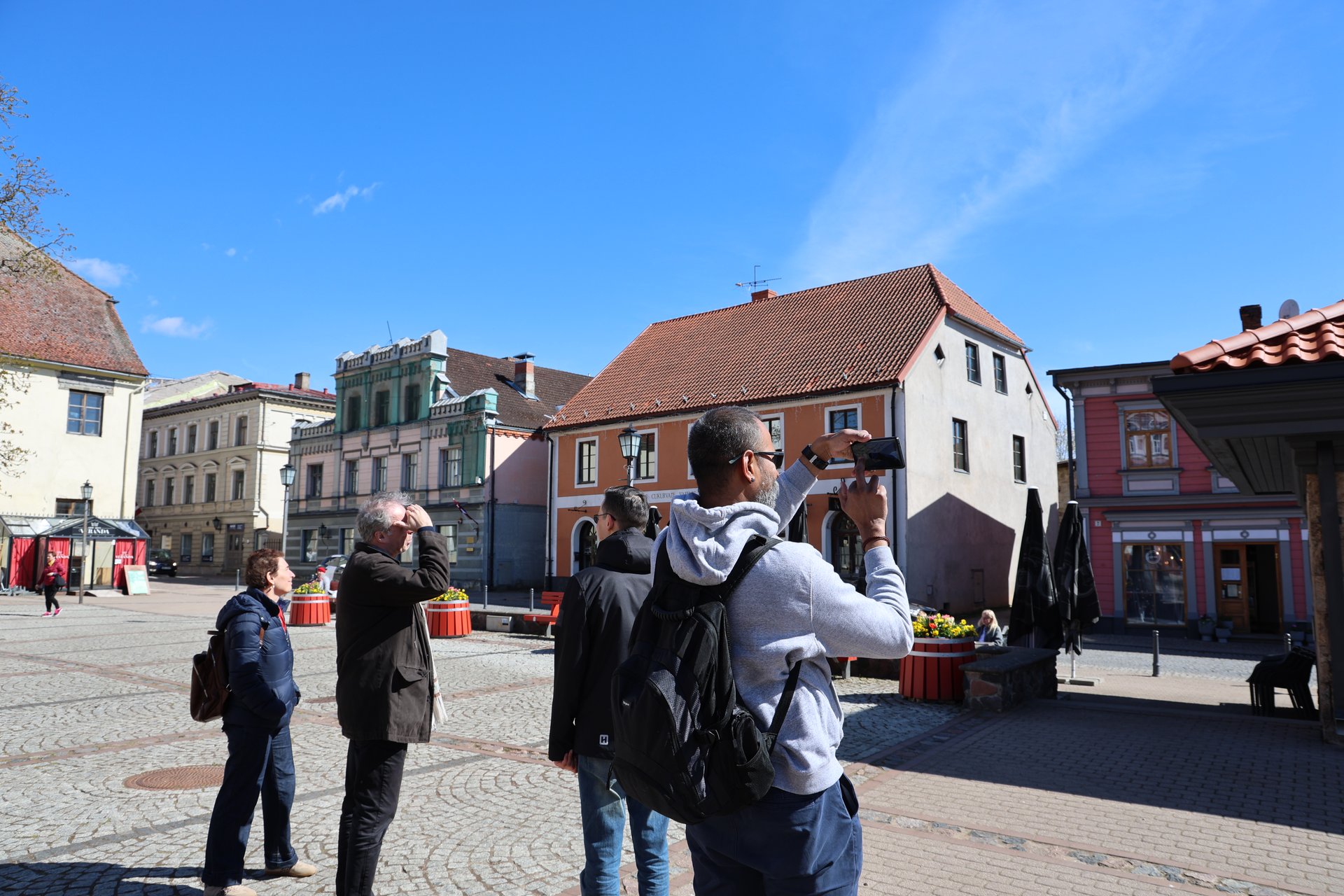 Tour group photographing heritage facades on Cēsis old town square