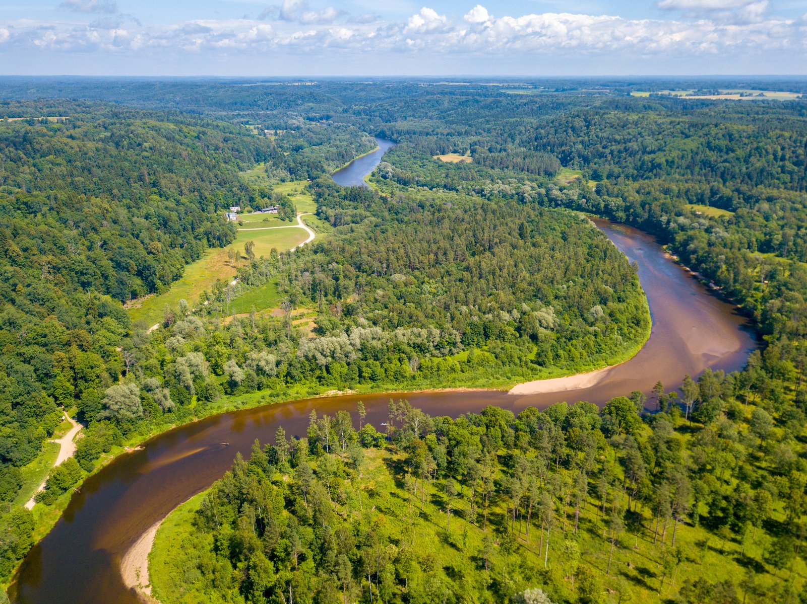 The Gauja river winding through forested valley slopes, aerial view
