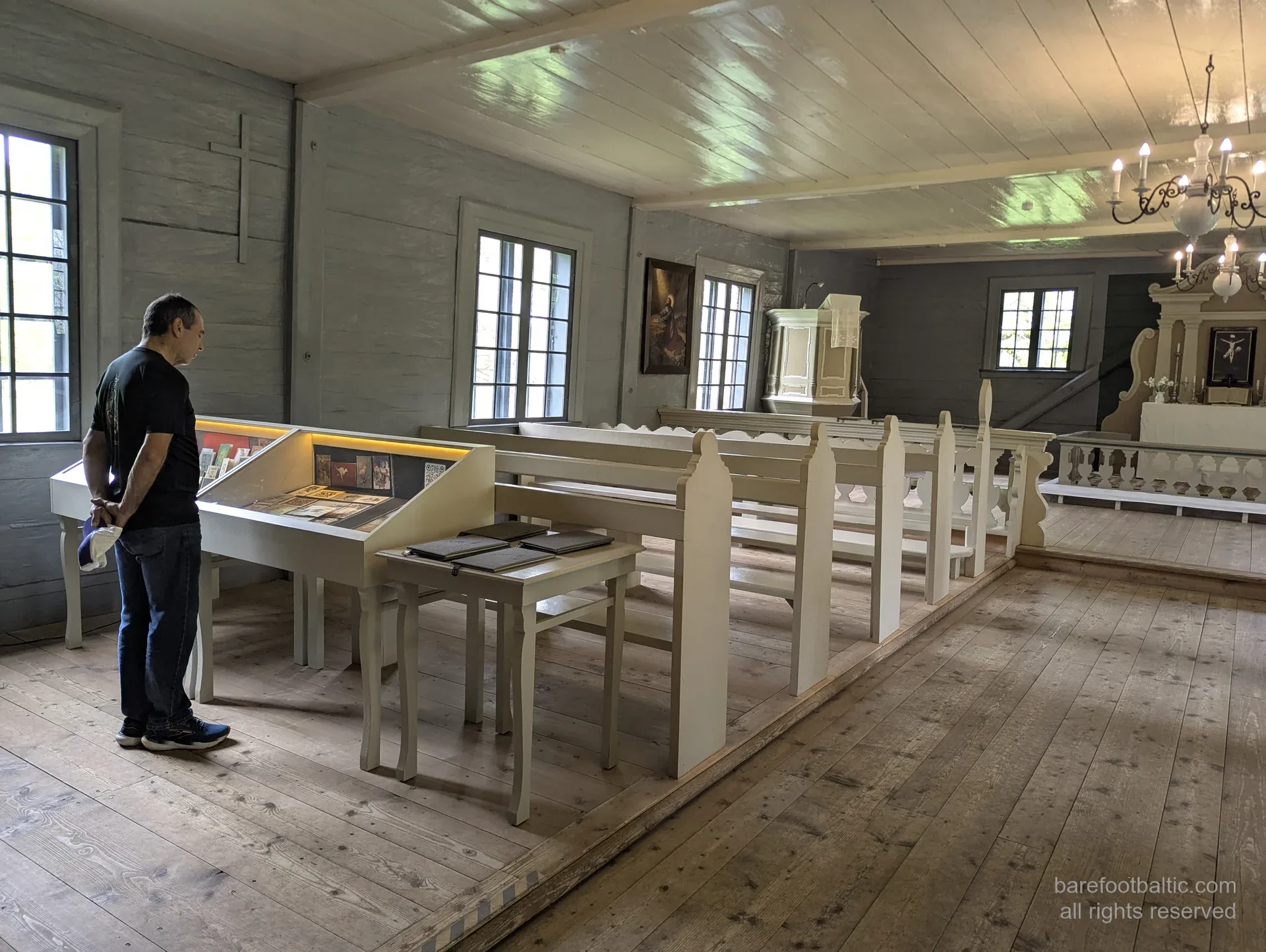 Wooden Vidzeme heritage church museum interior with a guest viewing exhibits