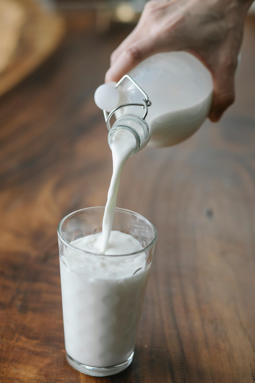 Latvian kefir being poured from a bottle into a glass on a wooden table