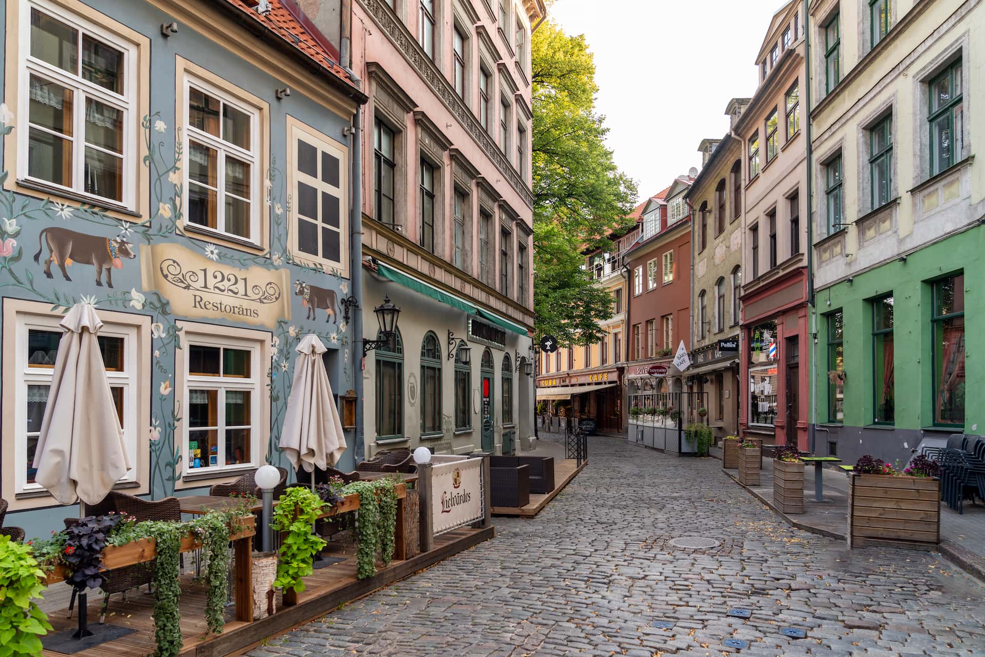 Cobblestone street with restaurants in Riga Old Town, the kind of evening view a first-time visitor walks into
